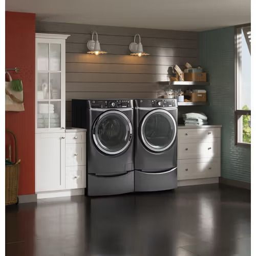 Laundry room with dark grey washer and dryer. Red, gray, and white walls with white cabinetry.