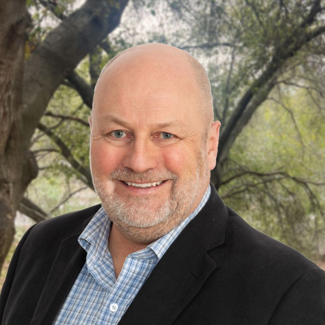 A man in a suit and plaid shirt is smiling for the camera.