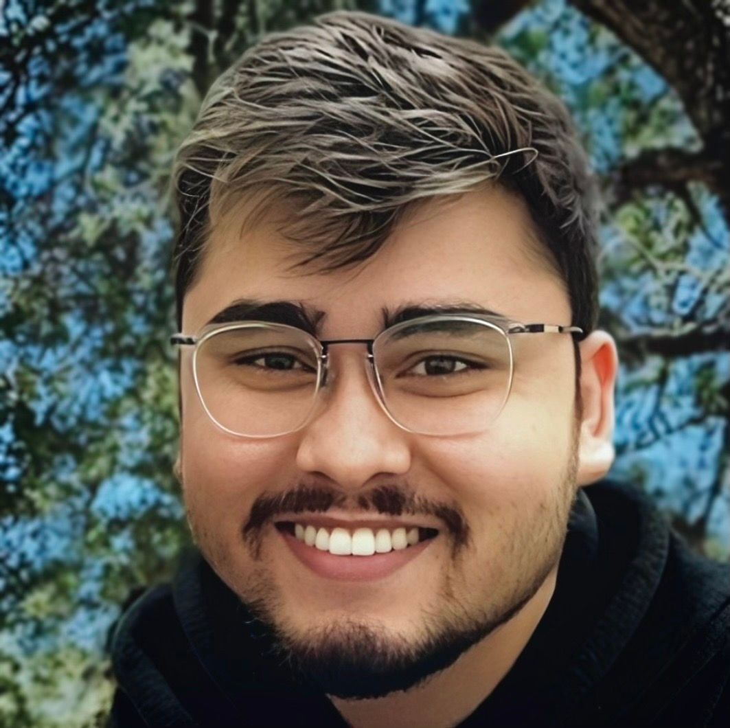 A man with glasses and a beard is smiling for the camera