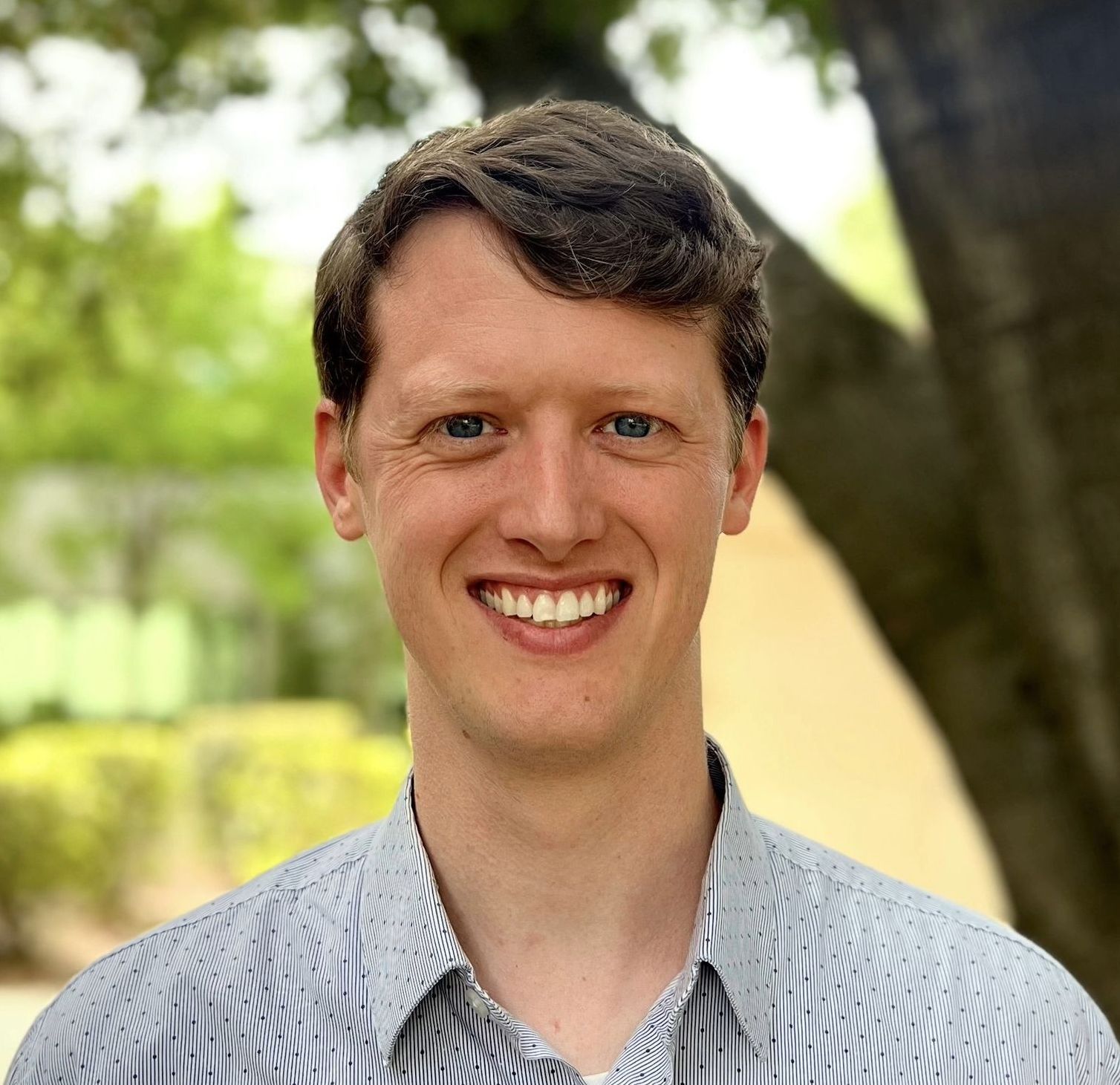 A man in a striped shirt is smiling for the camera