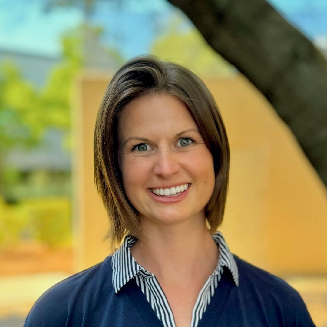 A woman in a striped shirt is smiling for the camera