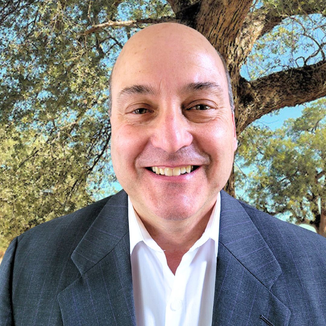 A man in a suit and plaid shirt is smiling for the camera.