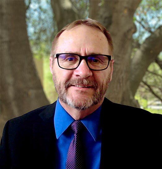 A man with a beard and glasses is wearing a suit and tie.