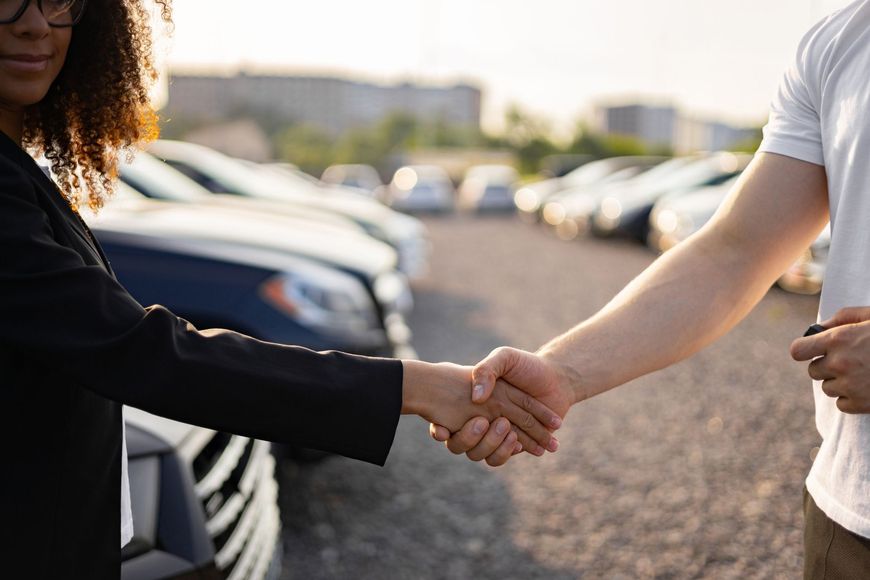 Una persona stringe la mano a un'altra davanti a un parcheggio.