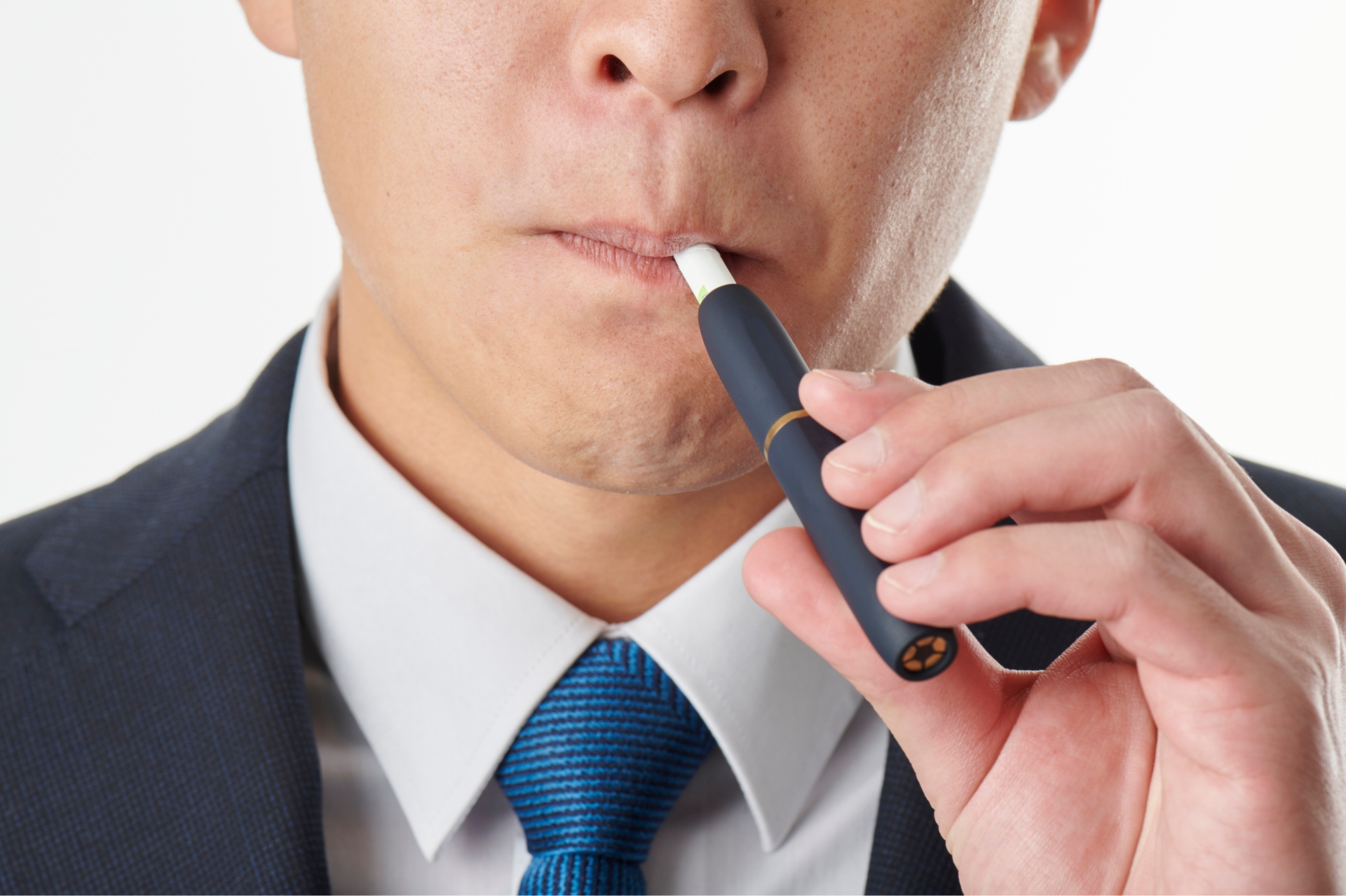 Person in suit using a dark blue heated tobacco device, white tip.