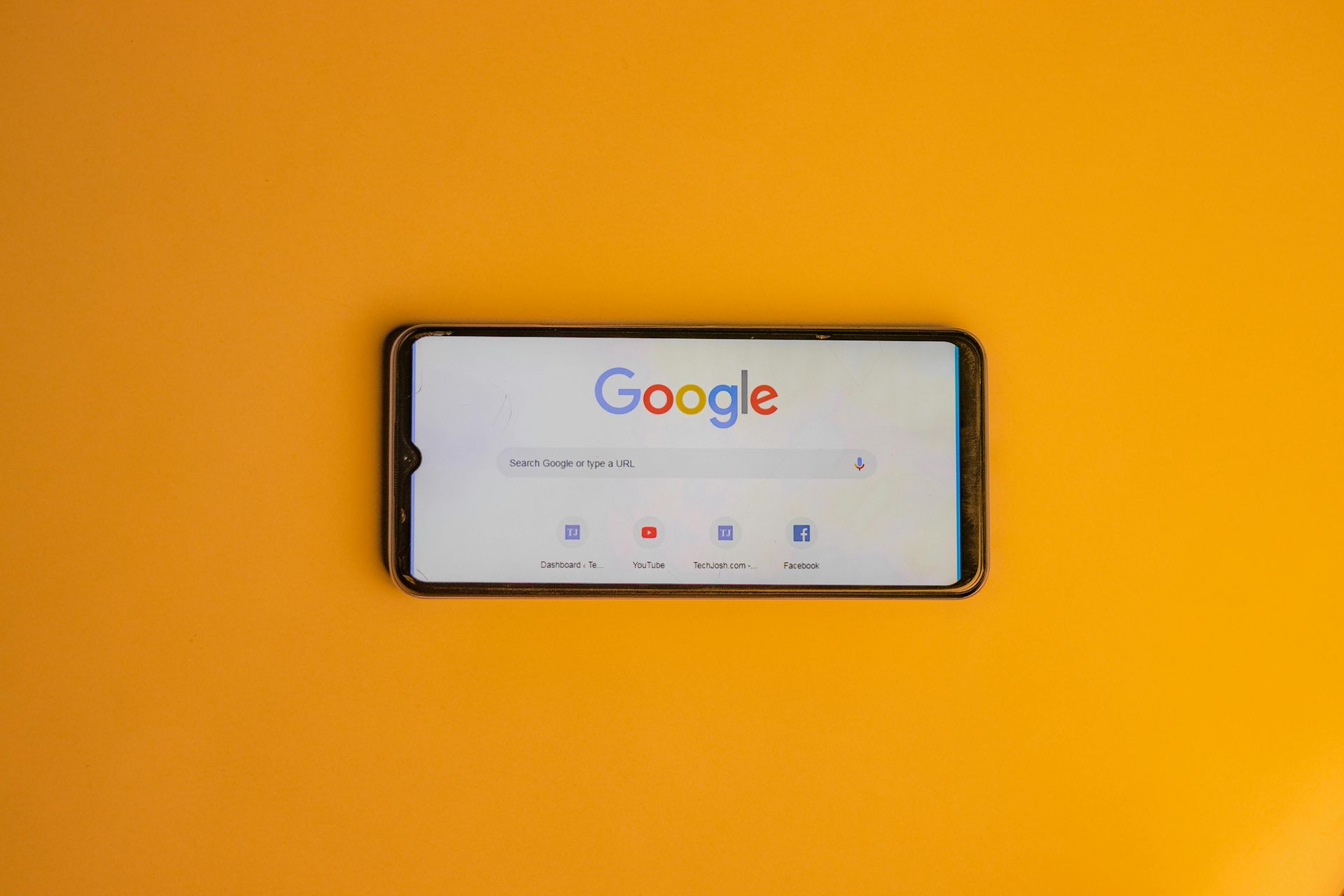 Smartphone mit der Google-Startseite auf hellgelbem Hintergrund