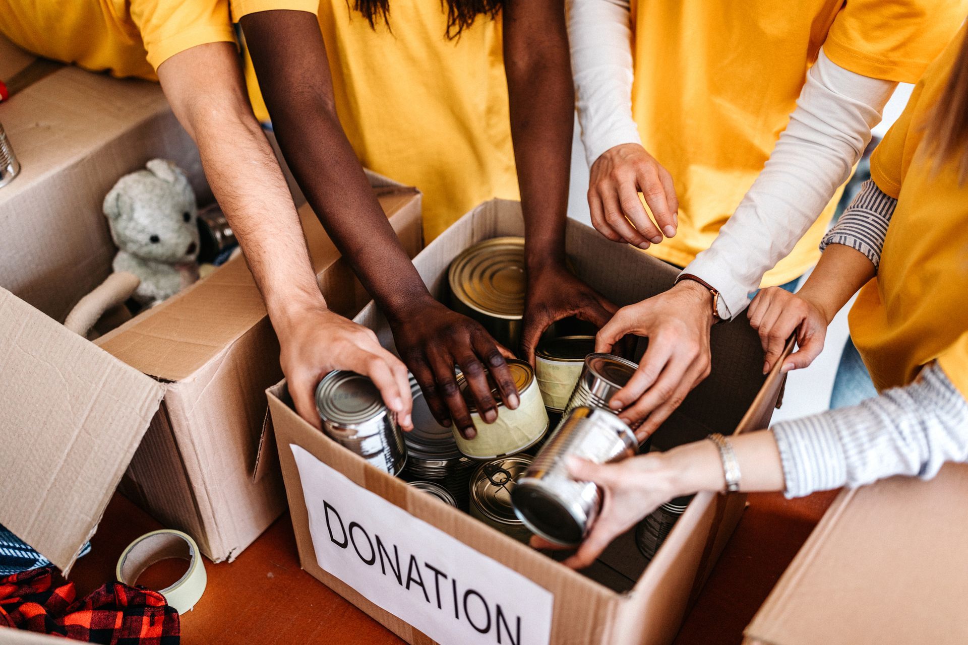 A group of people are putting cans into a donation box.
