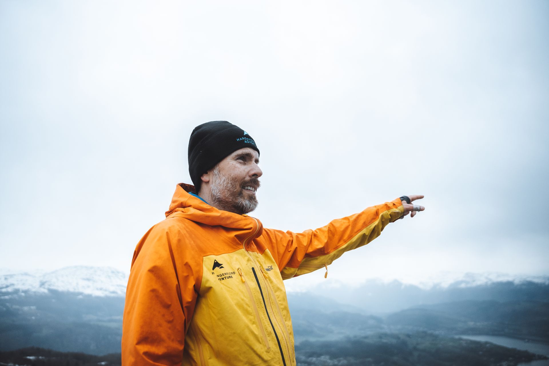 Guide pointing into the fjord mountains