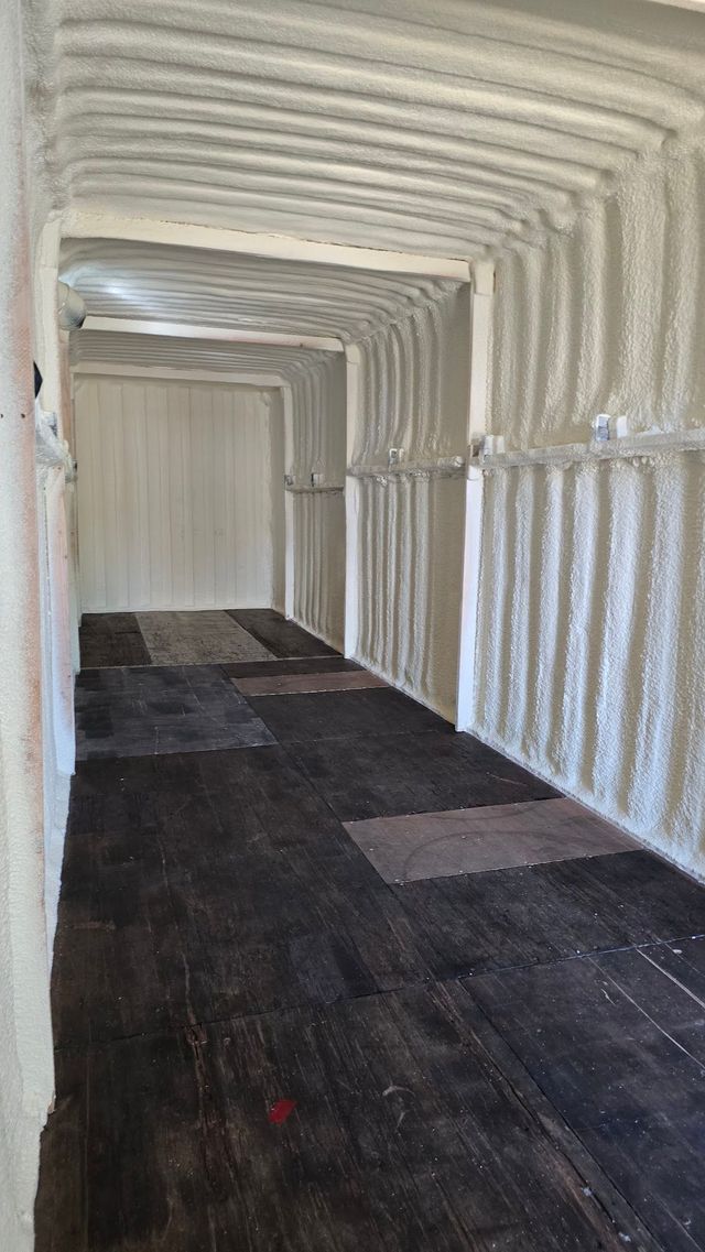 Empty covered walkway with white arched walls and dark floor tiles