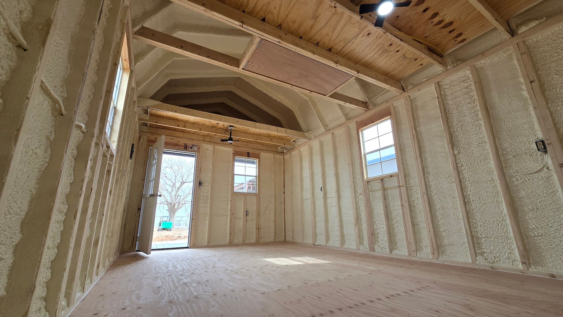Interior of an unfinished house with exposed wood framing, insulation, and windows under construction