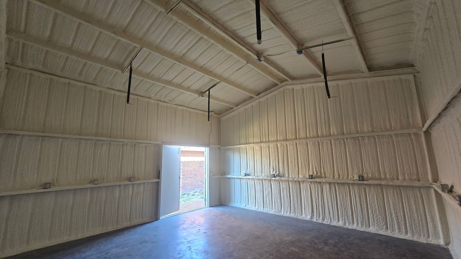 Empty insulated warehouse interior with corrugated metal walls and an open doorway