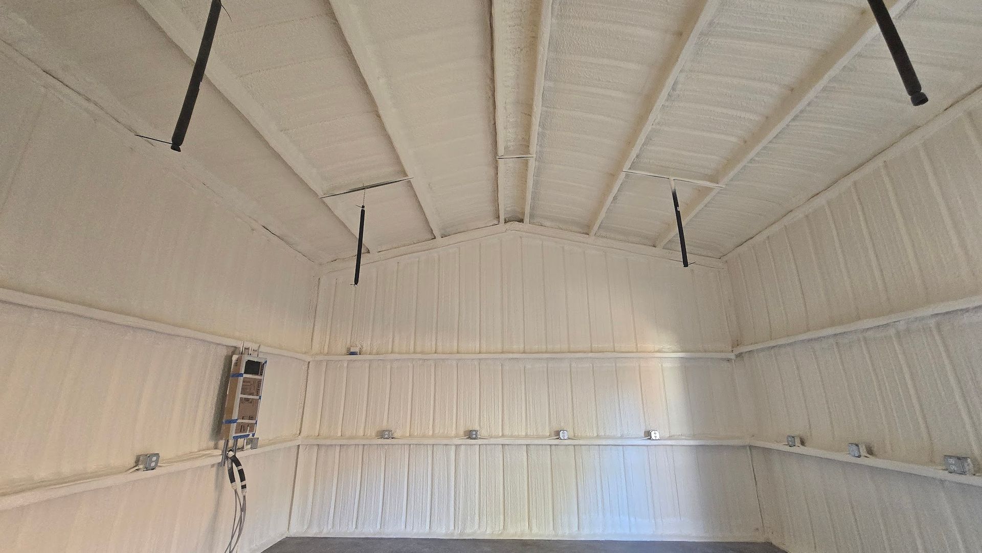 Interior of a white domed structure with curved walls and hanging black cables or beams.