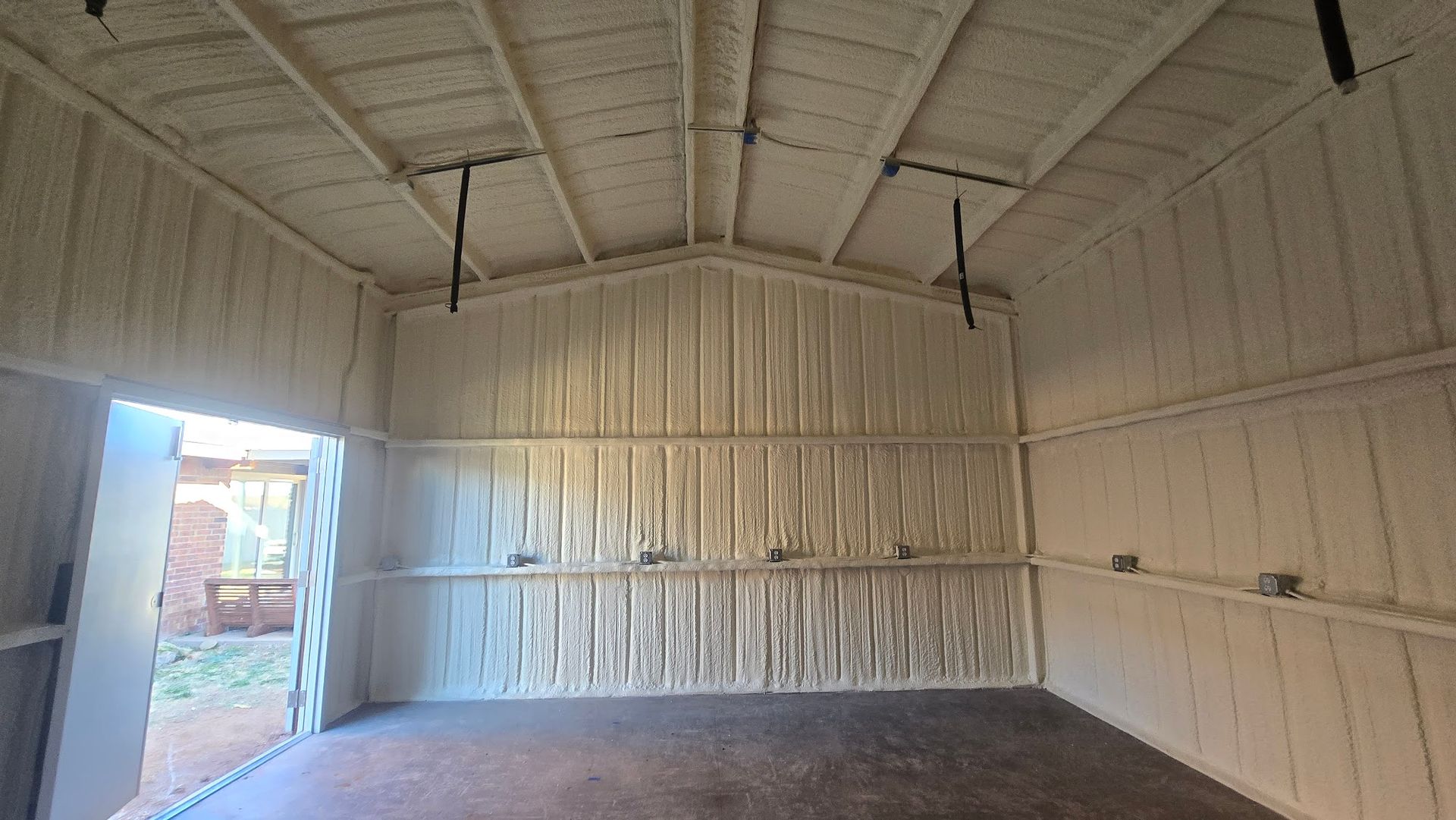 Empty white-painted warehouse interior with open door and concrete floor