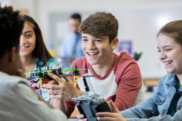 4 teens smiling at a table holding engineering materials