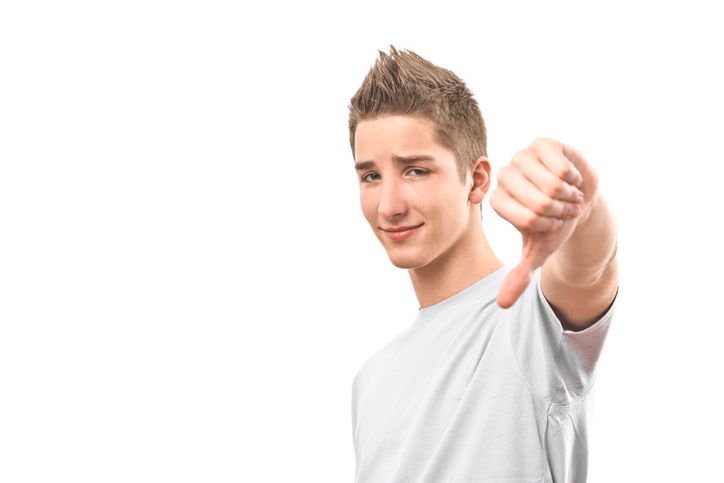 Teenage boy looking at the camera and giving a thumbs down