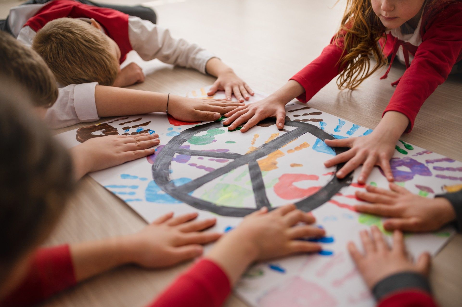 A Group of Children Are Laying on The Floor with Their Hands on A Peace Sign.