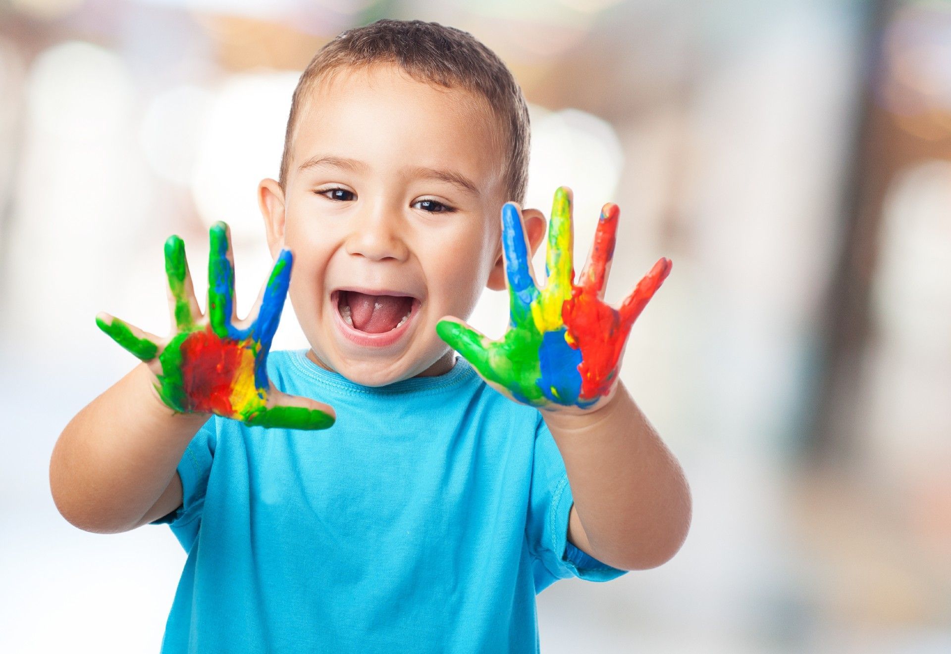 A Young Boy Is Holding His Hands Painted in Different Colors.