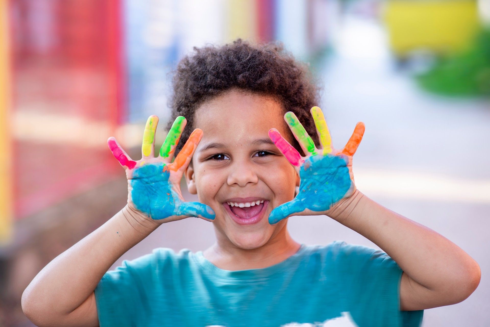 A Young Boy Is Making a Face with His Hands Painted in Different Colors.