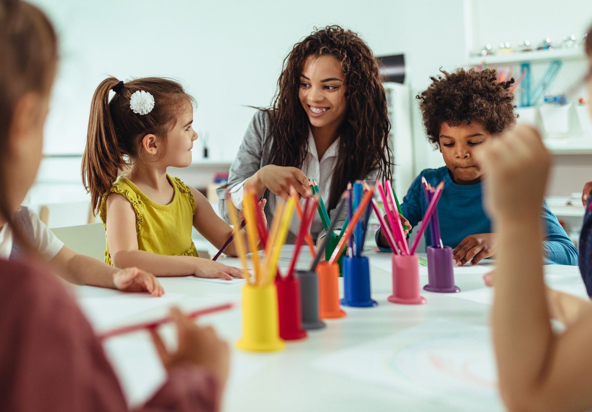 A Group of Children Are Sitting Around a Table with Colored Pencils.