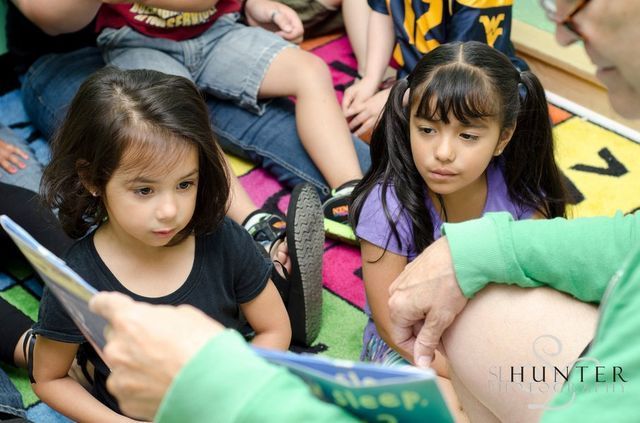 A Man Is Reading a Book to A Group of Young Girls