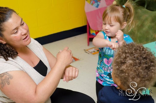 A Woman Is Sitting on The Floor Talking to Two Children