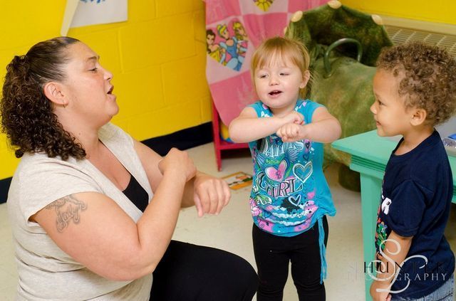 A Woman and Two Children Are Playing with Each Other in A Room.