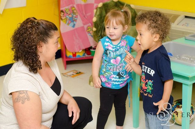 A Woman Is Kneeling Down Next to Two Children One of Whom Is Wearing a Shirt that Says Monster