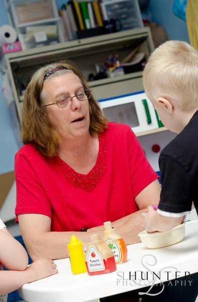 A Woman in A Red Shirt Is Sitting at A Table with Children.