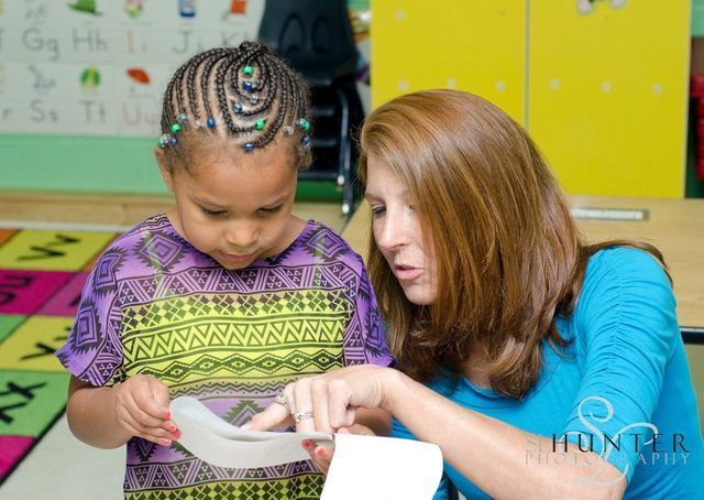 A Woman and A Little Girl Are Looking at A Piece of Paper.