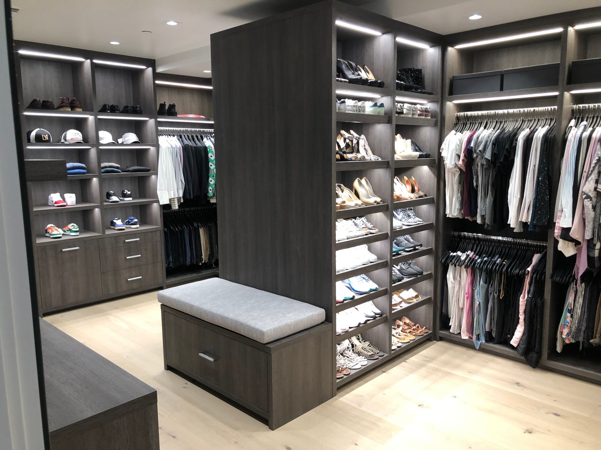 A walk in closet filled with lots of clothes and shoes.