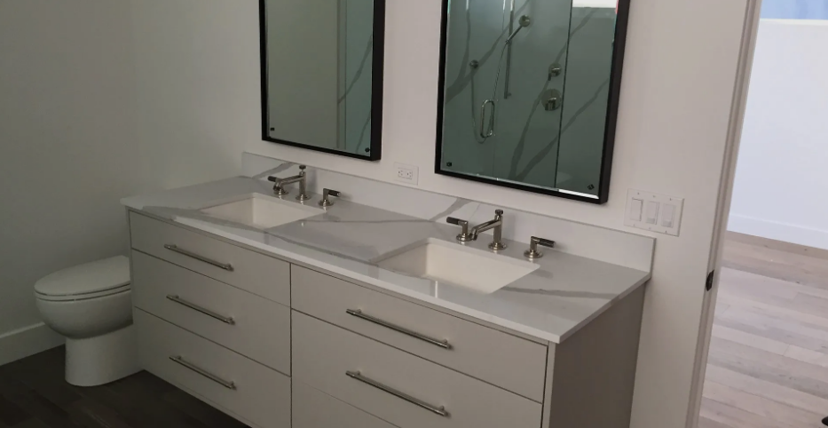 A bathroom with two sinks , two mirrors and a toilet.