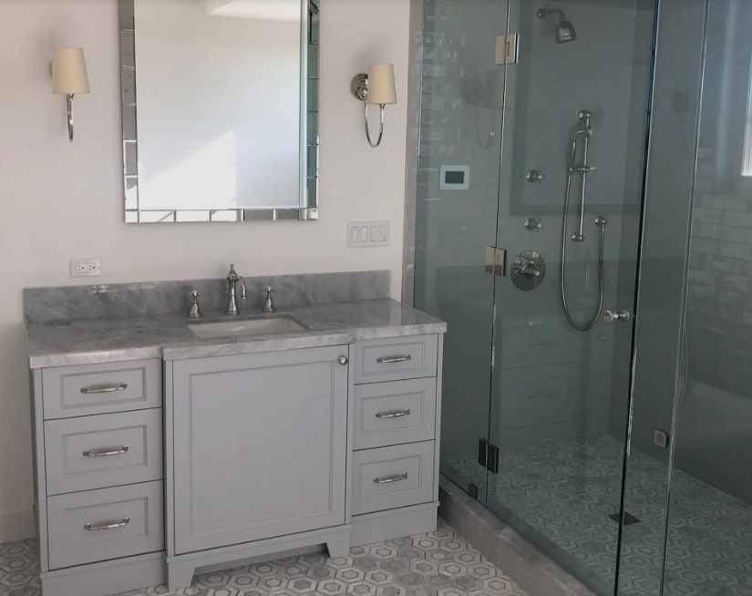 A bathroom with a sink a mirror and a walk in shower