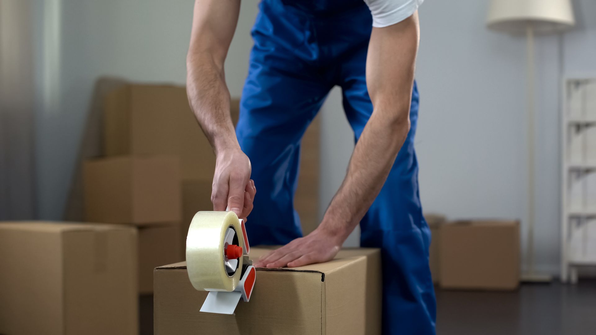 Local moving company worker taping a moving box