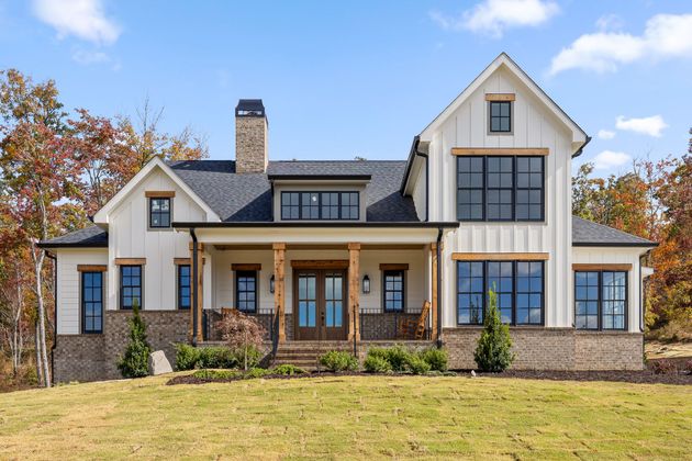 A custom home in River Gorge Ranch from NuHaven Homes that features a Modern two-story house with stone accents, large windows, and a front porch on a sunny lawn