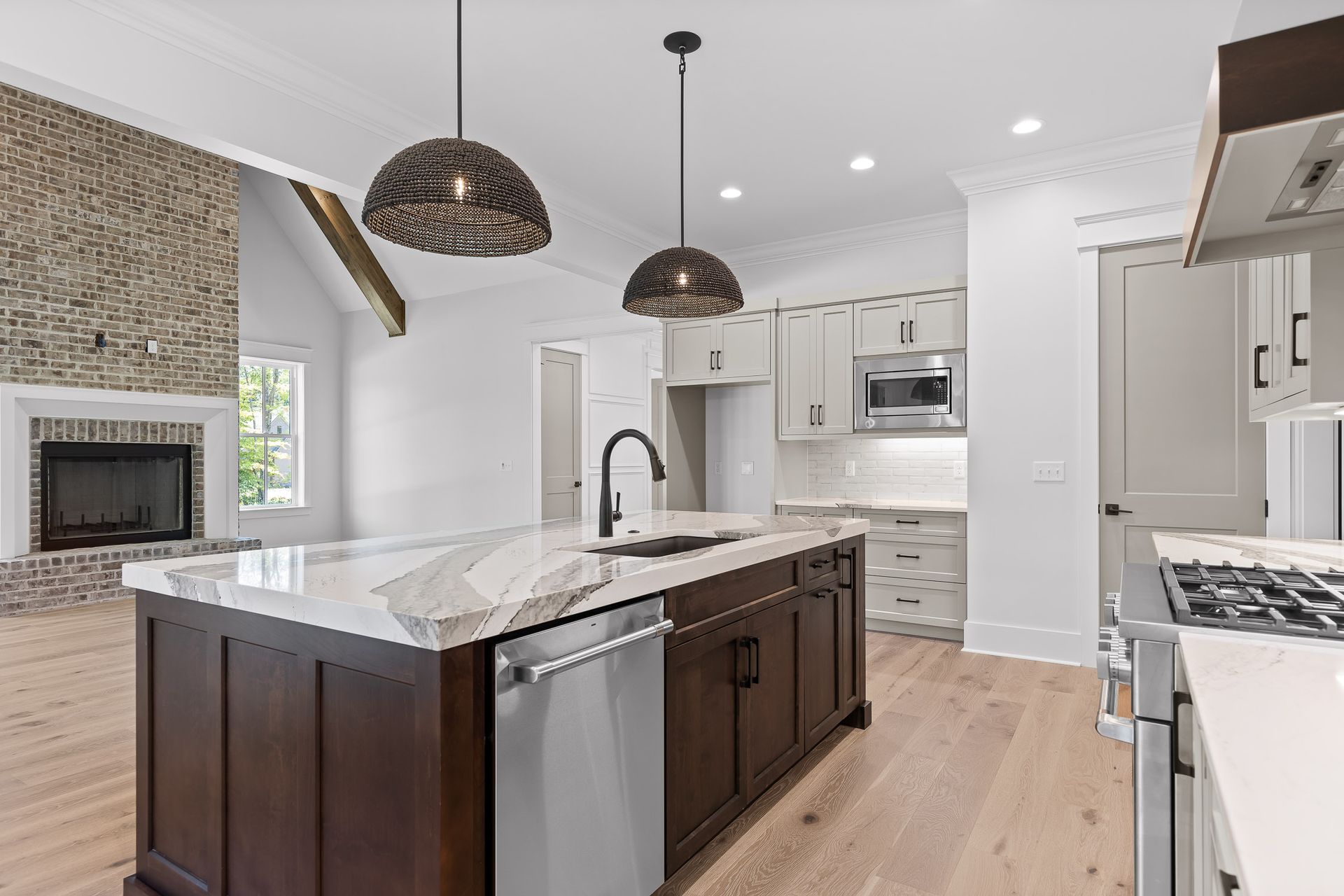 Bright modern kitchen with a large island, white cabinets, pendant lights, and stainless steel appliances