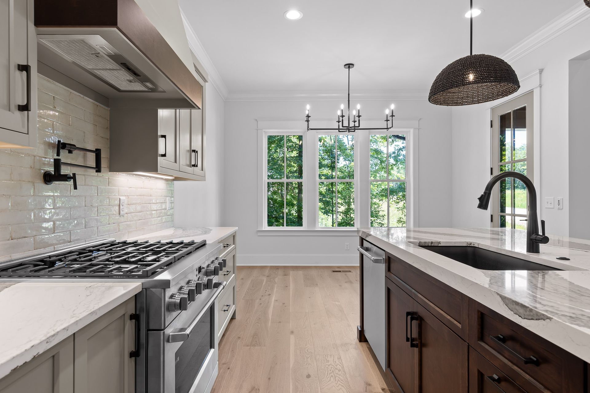 Modern kitchen with white cabinets, dark island, stainless appliances, and a window view.