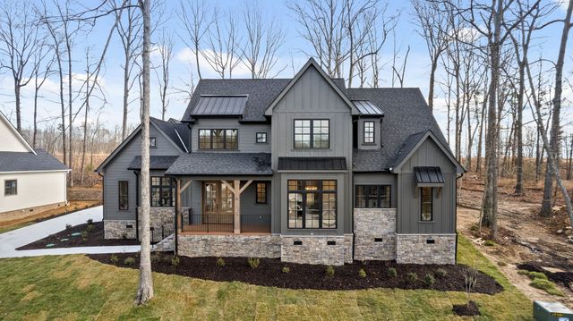 Modern gray two-story house with stone facade and a covered front porch in a wooded setting