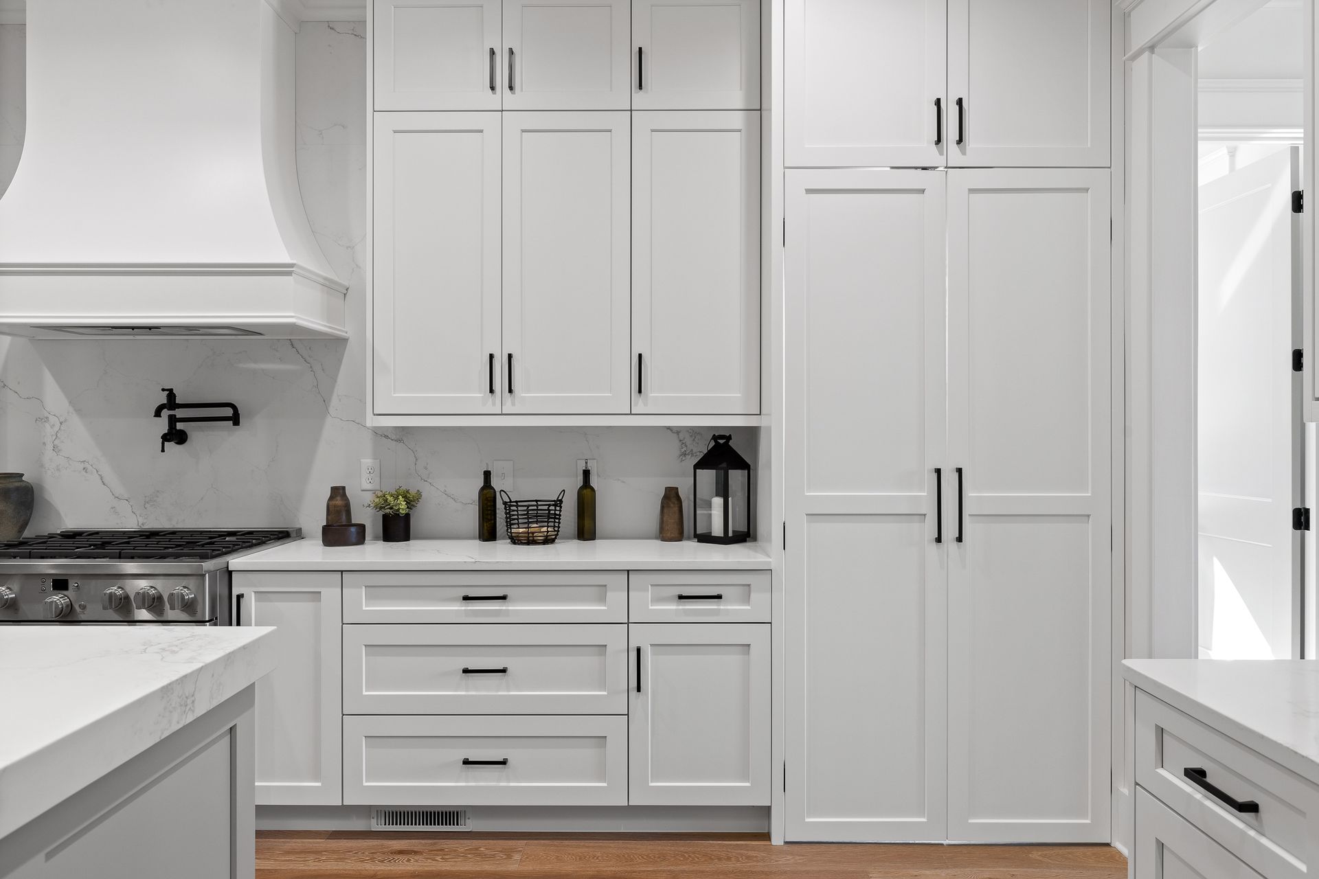 Bright white modern kitchen with cabinets, stove, and countertop accessories