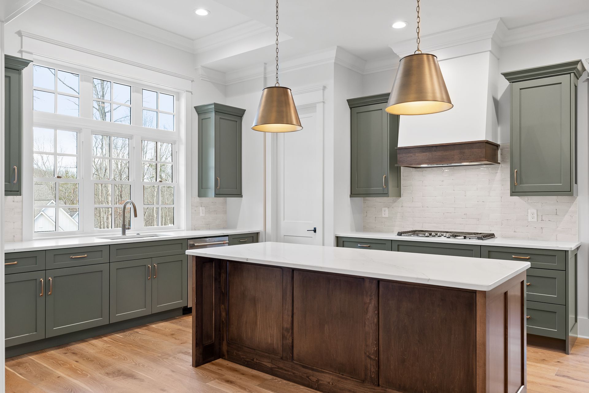 Bright modern kitchen with light wood and gray cabinets, white island, marble backsplash, and stainless steel fridge