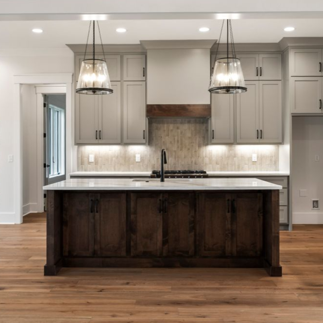 Modern kitchen with dark island, gray cabinets, pendant lights, and wood flooring