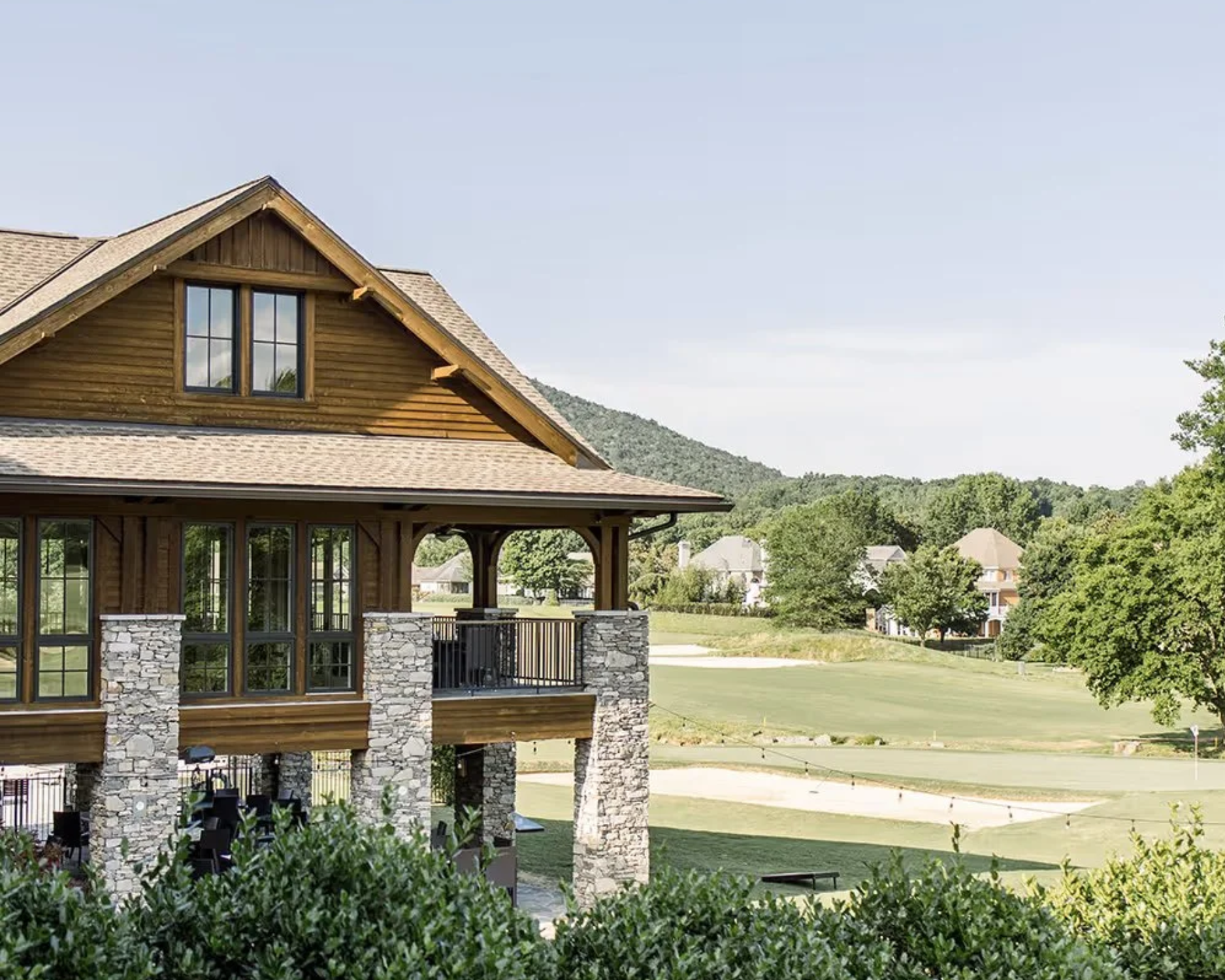 Rustic cabin on stone pillars overlooking a green golf course and trees
