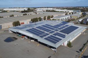 Large warehouse roof covered with solar panels in an industrial area