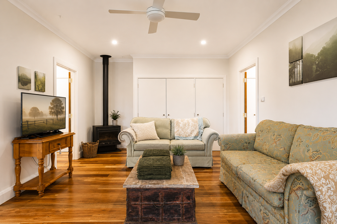 Bright living room with wood floors, beige sofas, coffee table, TV, and white closet doors