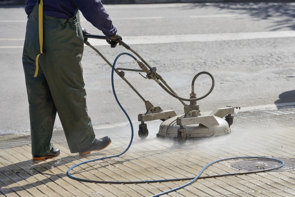 A man is using a high pressure washer to clean a roof.