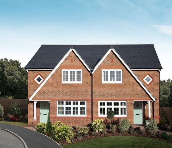 Two brick semi-detached houses with black roofs, white windows, and green doors.
