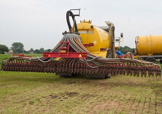 A yellow and red tractor is plowing a field