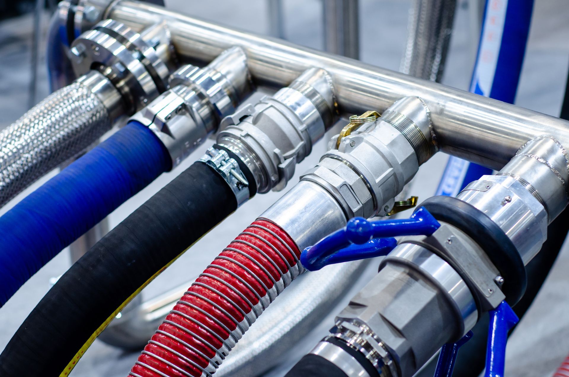 A set of 5 industrial hoses of different colors connected to a steel pipe