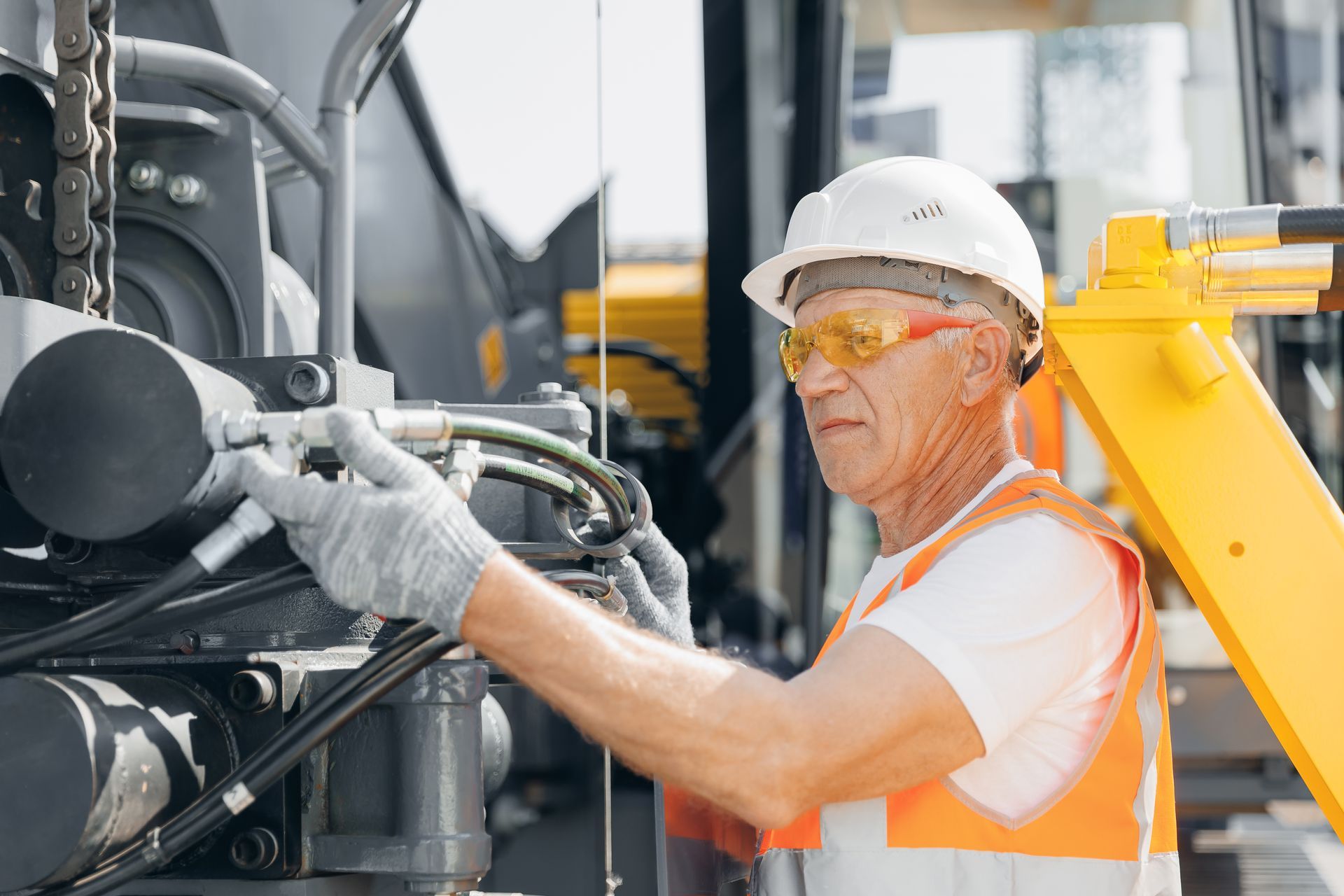 A hydraulic engineer is doing a safety check on hoses of a modern drilling industrial machine.