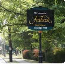 A welcome to frederick maryland sign is sitting on the side of a road. A welcome to frederick maryland sign is sitting on the side of a road.