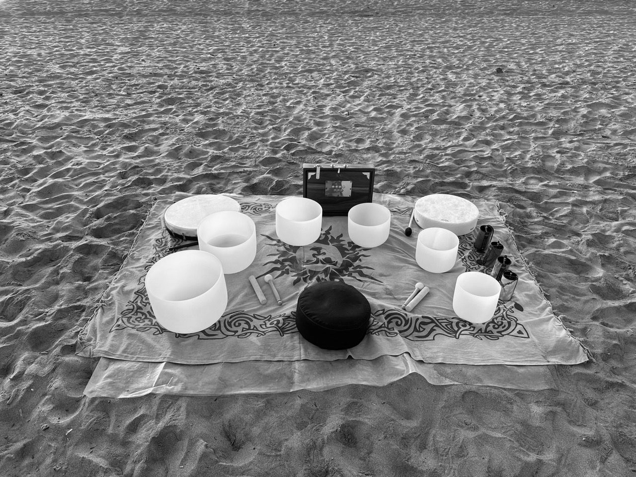 Allestimento da campeggio con lanterne e ciotole disposte su una coperta su una spiaggia sabbiosa.